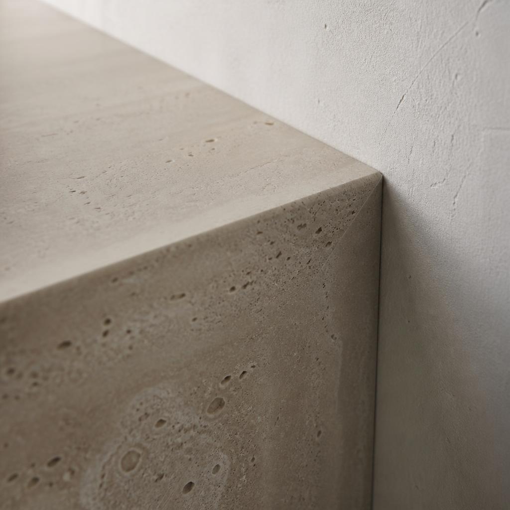 Edge of honed travertine against a plaster wall